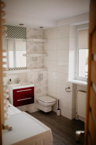 a white bathroom with a toilet and a sink at Dom na Lawendowej in Głuszyca