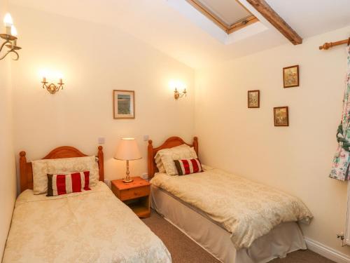 巴恩斯特珀爾的住宿－Ridge Cottage，一间卧室设有两张床和一张桌子上的台灯。