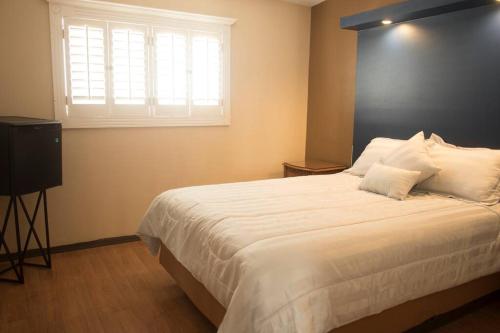 - une chambre avec un grand lit blanc et une fenêtre dans l'établissement Bonita y cómoda casa cerca del consulado., à Ciudad Juárez