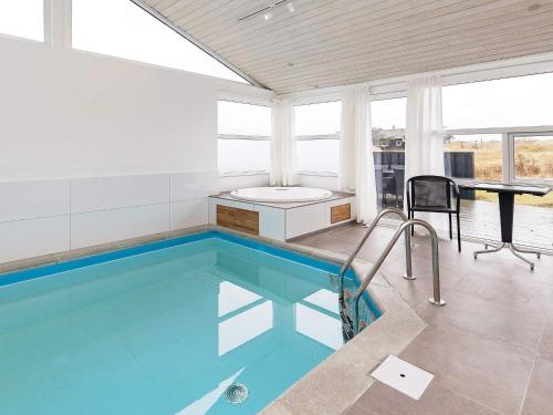 a swimming pool in a house with a table and chairs at 12 person holiday home in Pandrup in Rødhus