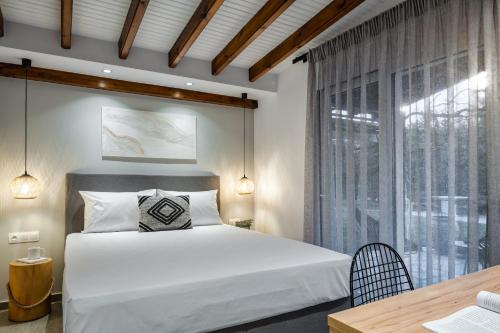 sypialnia z łóżkiem, stołem i oknem w obiekcie Coel Luxury Suites by RentalsPro Services - Potidea Halkidiki w mieście Nea Potidaea