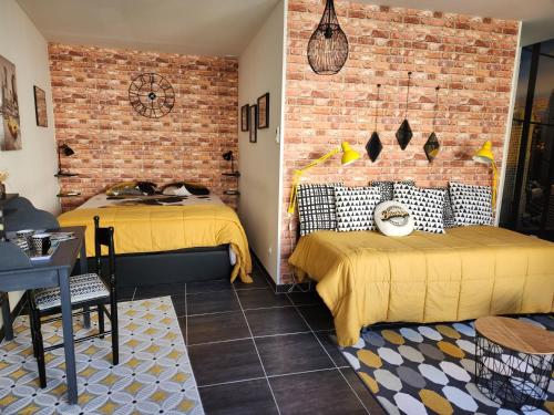 a bedroom with two beds and a brick wall at Le clos Pascaline in Noyers-sur-Cher