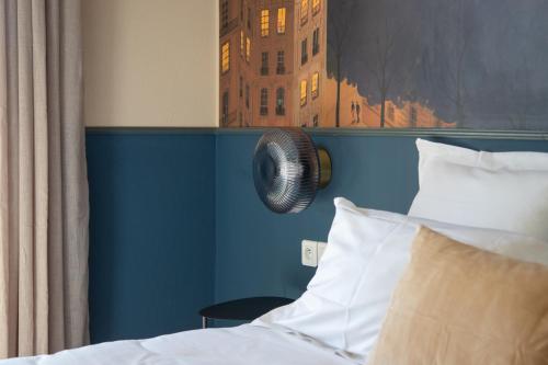 a bedroom with a bed with a blue wall and a fan at Hôtel La Perna in Pernes-les-Fontaines