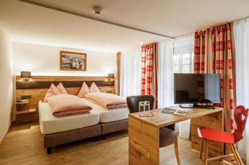 ヴィルダースヴィルにあるAlpenblick Hotel & Restaurant Wilderswil by Interlakenのベッドとデスクが備わるホテルルームです。