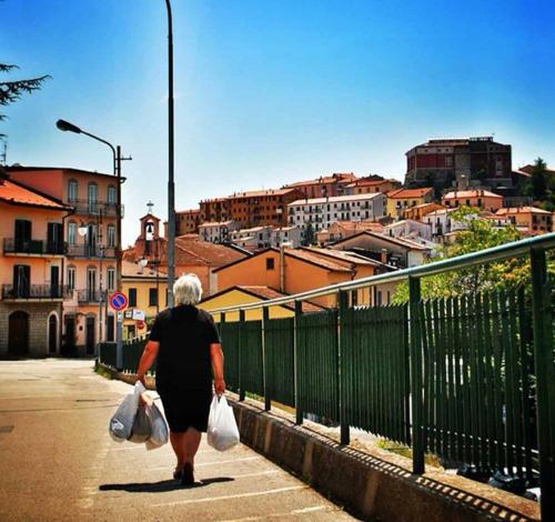 an older woman walking down a street with shopping bags at La casa nel Borgo in Bella