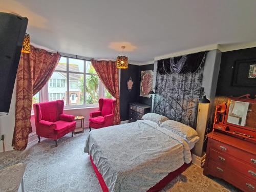 a bedroom with a bed and two pink chairs at The Miggi vegan guesthouse in Torquay