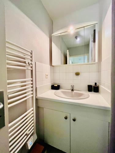 une salle de bain blanche avec un lavabo et un miroir dans l'établissement Le Briantais, à Saint-Malo