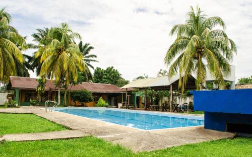 a swimming pool in front of a house with palm trees at Hostel Casa de las Palmas Tours in Leticia