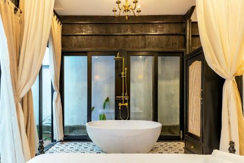 un bagno con vasca in una camera con finestre di Lover's Retreat Villa Hoi An a Hoi An