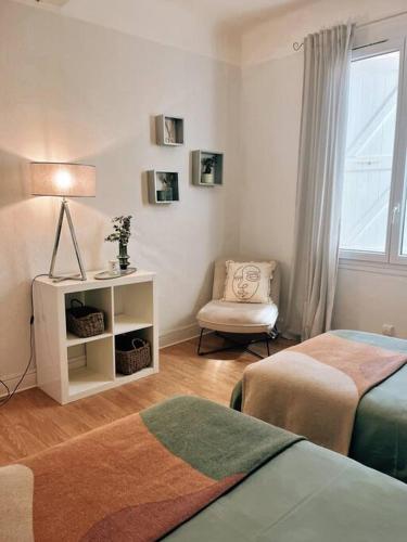 a bedroom with two beds and a chair and a window at Appartement chaleureux au centre du village in Montesquieu-Volvestre