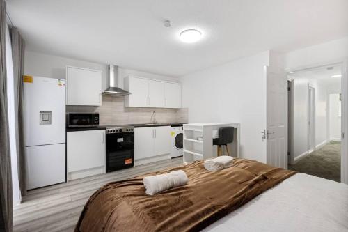 a bedroom with a bed and a kitchen with white cabinets at Stylish Studio room in Mill Hill in Edgware