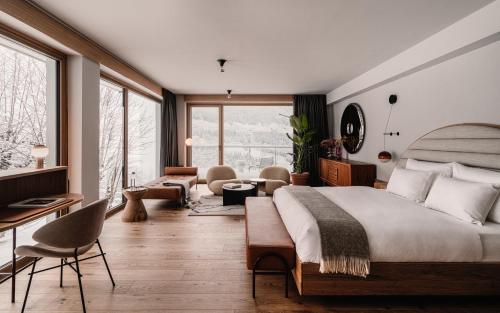 The Comodo Bad Gastein, a Member of Design Hotels في باد جاستاين: غرفة نوم بسرير كبير وغرفة معيشة