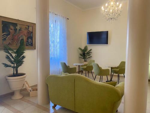 een woonkamer met een groene bank en stoelen bij Hotel Virginia in Marina di Massa