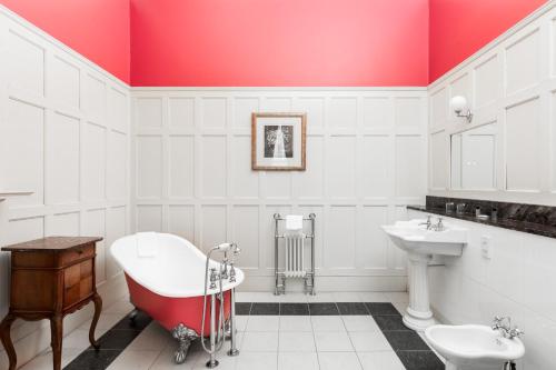 uma casa de banho com um tecto vermelho, uma banheira e um lavatório. em Fernhill Hotel em Portpatrick