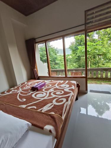 a bed in a room with a large window at Made Oka Budget Room in Munduk