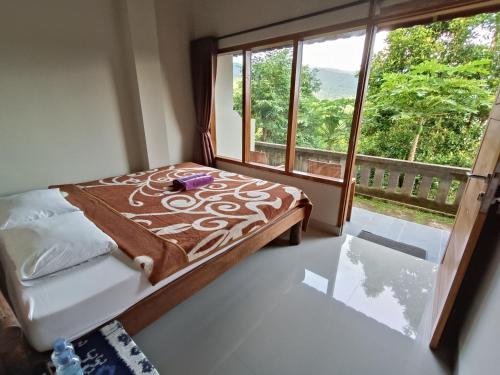 een slaapkamer met een bed en een groot raam bij Made Oka Budget Room in Munduk