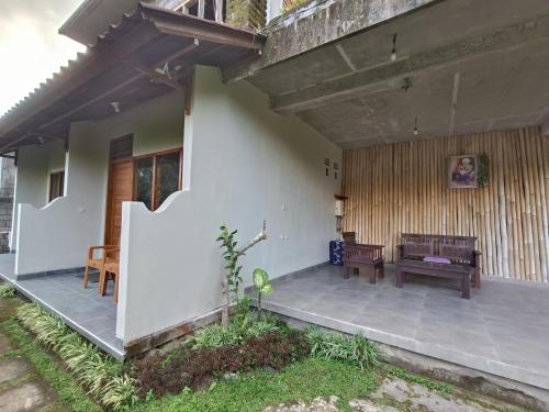 a porch of a house with a bench and a table at Made Oka Budget Room in Munduk