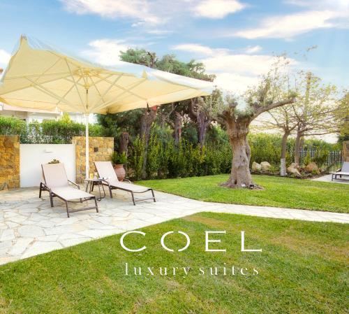 a patio with two chairs and an umbrella at Coel Luxury Suites by RentalsPro Services - Potidea Halkidiki in Nea Potidaea