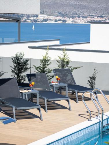 a row of chairs on the roof of a building with a pool at Villas Residence 360 in Trogir