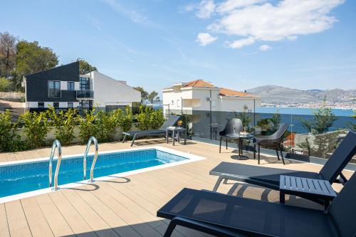 a patio with a pool and chairs next to a house at Villas Residence 360 in Trogir