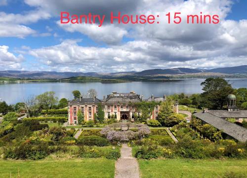 a large house with a lake in the background at Streamside B and B with Parking in Drom dhá Liag