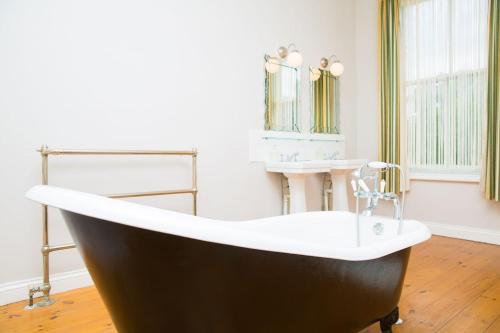 bañera en una habitación con lavabo en The Grange Manor House, Norfolk, en Setchey