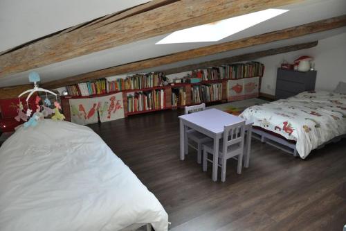 sypialnia z 2 łóżkami, stołem i półkami na książki w obiekcie La Grande Maison Rouge w mieście Mèze