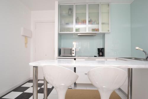 eine Küche mit einer weißen Theke und 2 weißen Stühlen in der Unterkunft Viva Sitges - Mayo Terrace in Sitges