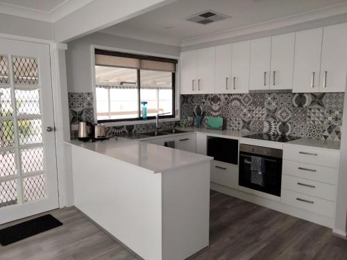 a kitchen with white cabinets and a white counter top at Birubi Beach House in Anna Bay