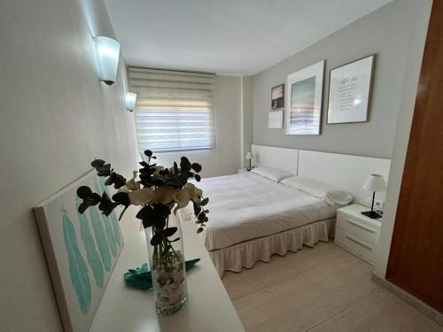 1 dormitorio con 1 cama y un jarrón de flores sobre una mesa en APARTAMENTO LOS GIRASOLES 1, en Salou