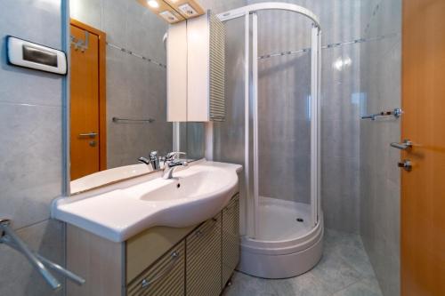 ein Bad mit einem Waschbecken und einer Dusche in der Unterkunft Grubelic House in Rab
