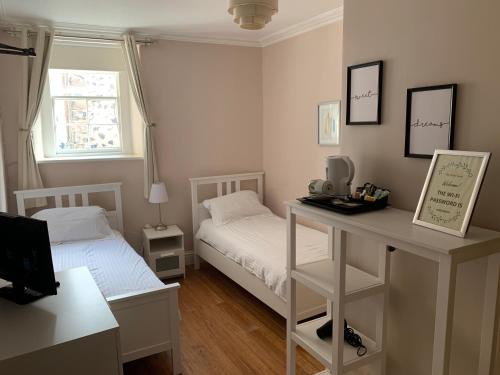a small bedroom with two beds and a desk at The White Swan Hotel in Duns