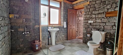 een stenen badkamer met een toilet en een wastafel bij The Hideaway Cottage in Kasauli