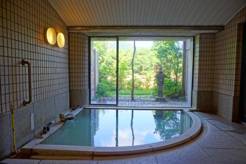 a swimming pool in a room with a window and a fountain at Lalaca in Hakone