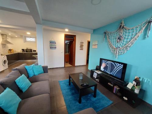 Una sala de estar con un sofá y un televisor. en O Cantinho do Zé, en Funchal