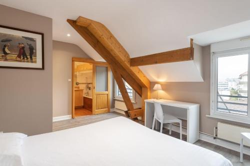 a bedroom with a bed and a desk and a window at Hôtel De La Paix in Gérardmer