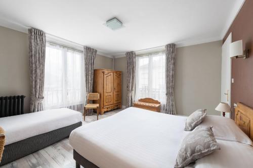 a bedroom with two beds and a chair and windows at Hôtel De La Paix in Gérardmer