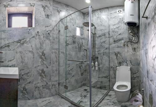 La salle de bains est pourvue d'une douche en verre et de toilettes. dans l'établissement Happy Flower Guesthouse, à Verkhnyaya Alaarcha