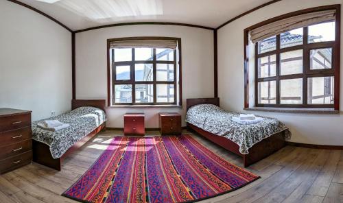 a room with two beds and a rug on the floor at Happy Flower Guesthouse in Verkhnyaya Alaarcha