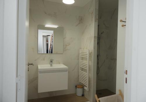 une salle de bain blanche avec un lavabo et un miroir dans l'établissement Ty Maec - Maison vue mer - Idéale pour le surf, kitesurf et la détente, à Saint-Pierre-Quiberon