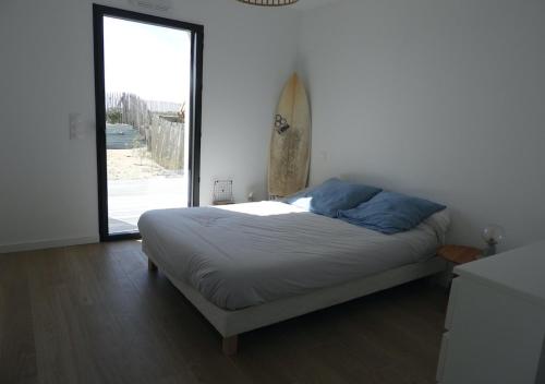 - une chambre avec un lit et une planche de surf sur le mur dans l'établissement Ty Maec - Maison vue mer - Idéale pour le surf, kitesurf et la détente, à Saint-Pierre-Quiberon