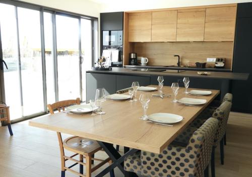 - une table en bois avec des assiettes et des verres à vin dans la cuisine dans l'établissement Ty Maec - Maison vue mer - Idéale pour le surf, kitesurf et la détente, à Saint-Pierre-Quiberon