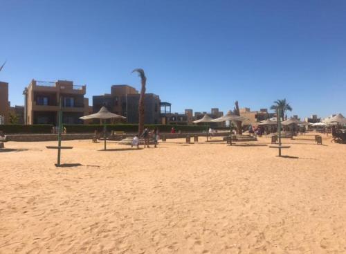 a sandy beach with umbrellas and people on it at شاليه للايجار في قريه لاجولي العين السخنه - للاسر فقط in Ain Sokhna
