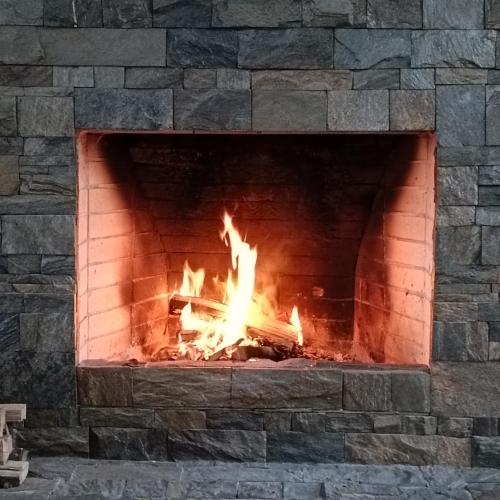 a brick fireplace with a fire in it at Happy Flower Guesthouse in Verkhnyaya Alaarcha