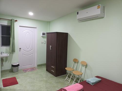 um quarto com uma cama e um armário e dois bancos em ชายเขาโฮมสเตย์ em Kanchanaburi