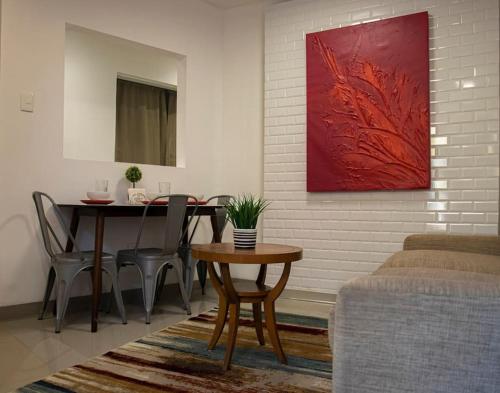 una sala de estar con una mesa y una pintura roja en Hermoso depa cerca de consulado, en Ciudad Juárez
