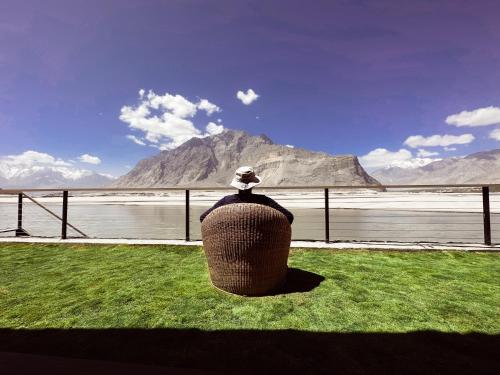 a person sitting on a bench looking out at the water at Khoj Resorts in Shigar