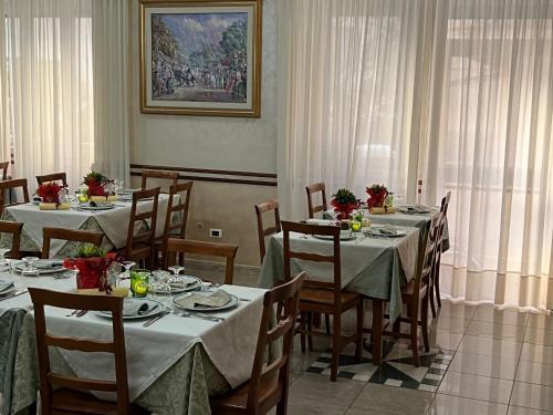 uma sala de jantar com mesas e cadeiras e um quadro em Hotel Rex em Praia a Mare