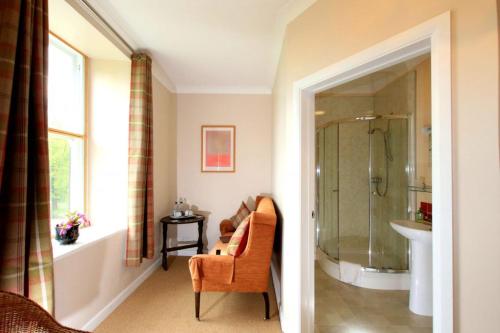 a bathroom with a shower and a chair and a sink at Cuffern Manor in Roch
