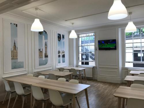 a restaurant with tables and chairs and a flat screen tv at Holland House (Victoria) in London